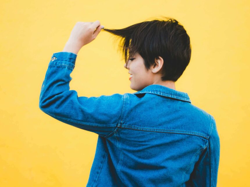 Woman with pixie cut pulling a few strands of hair