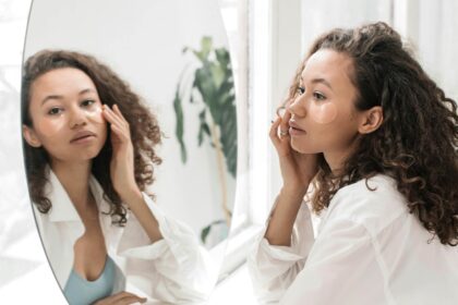 Woman applying cosmetics while looking at herself in the mirror