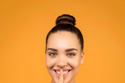 Young lady with hair bun against yellow background